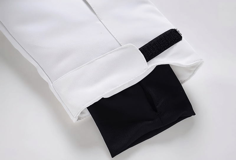 Close-up of the sleeve and double zipper of a white waterproof snowboarding jacket, highlighting its secure Velcro strap.